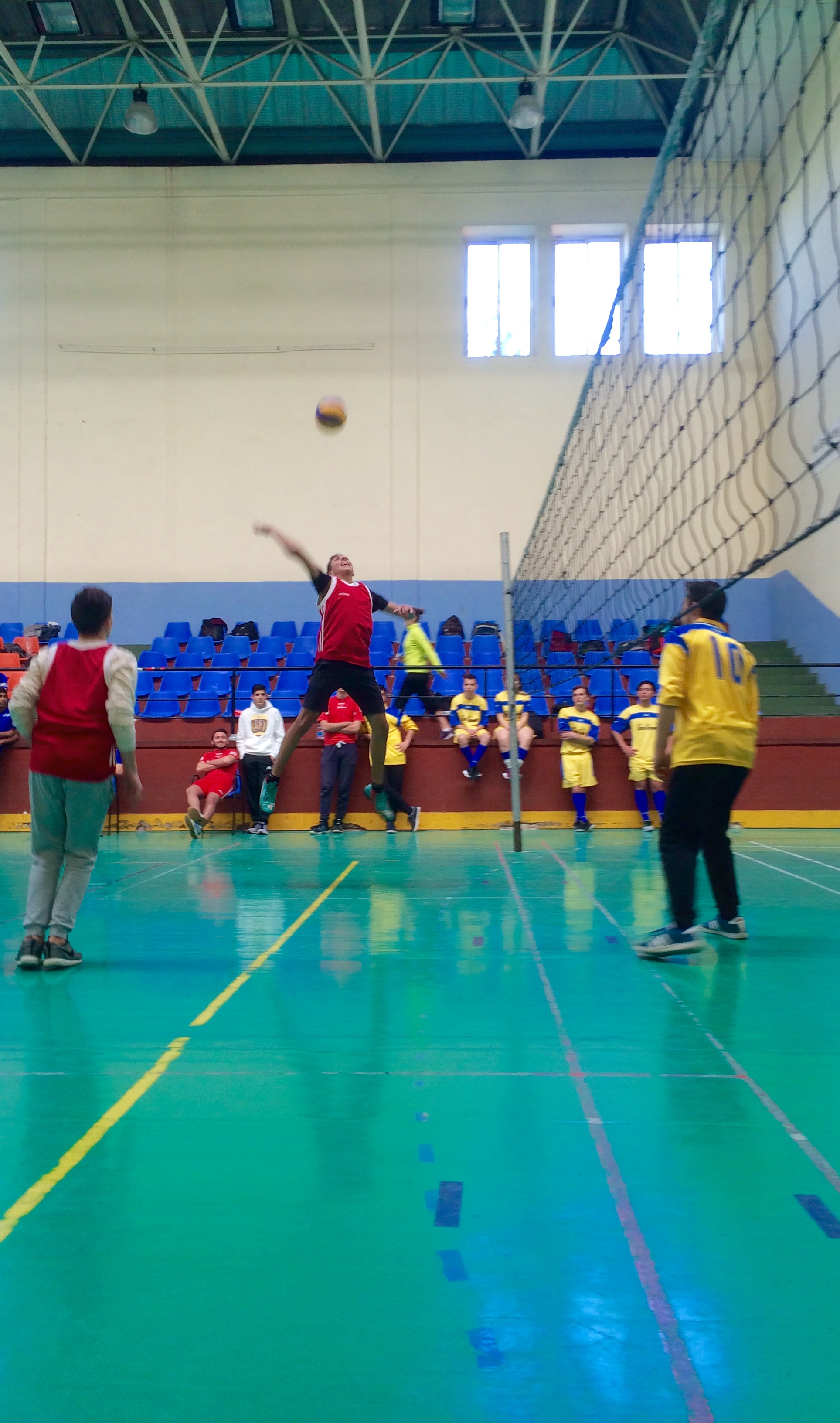 a student leaping in the air to hit a volleyball.