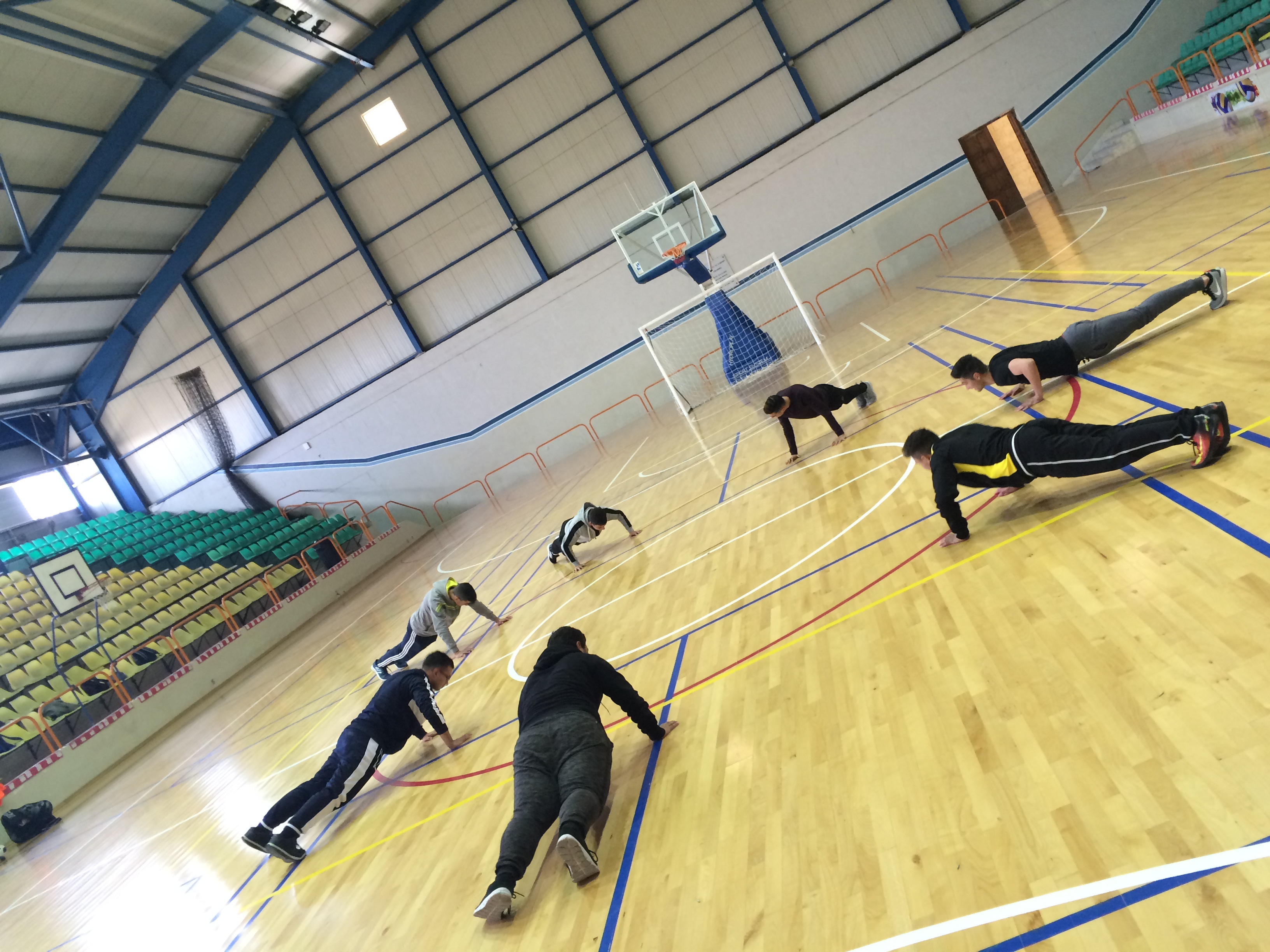 More students doing pushups in a gym.