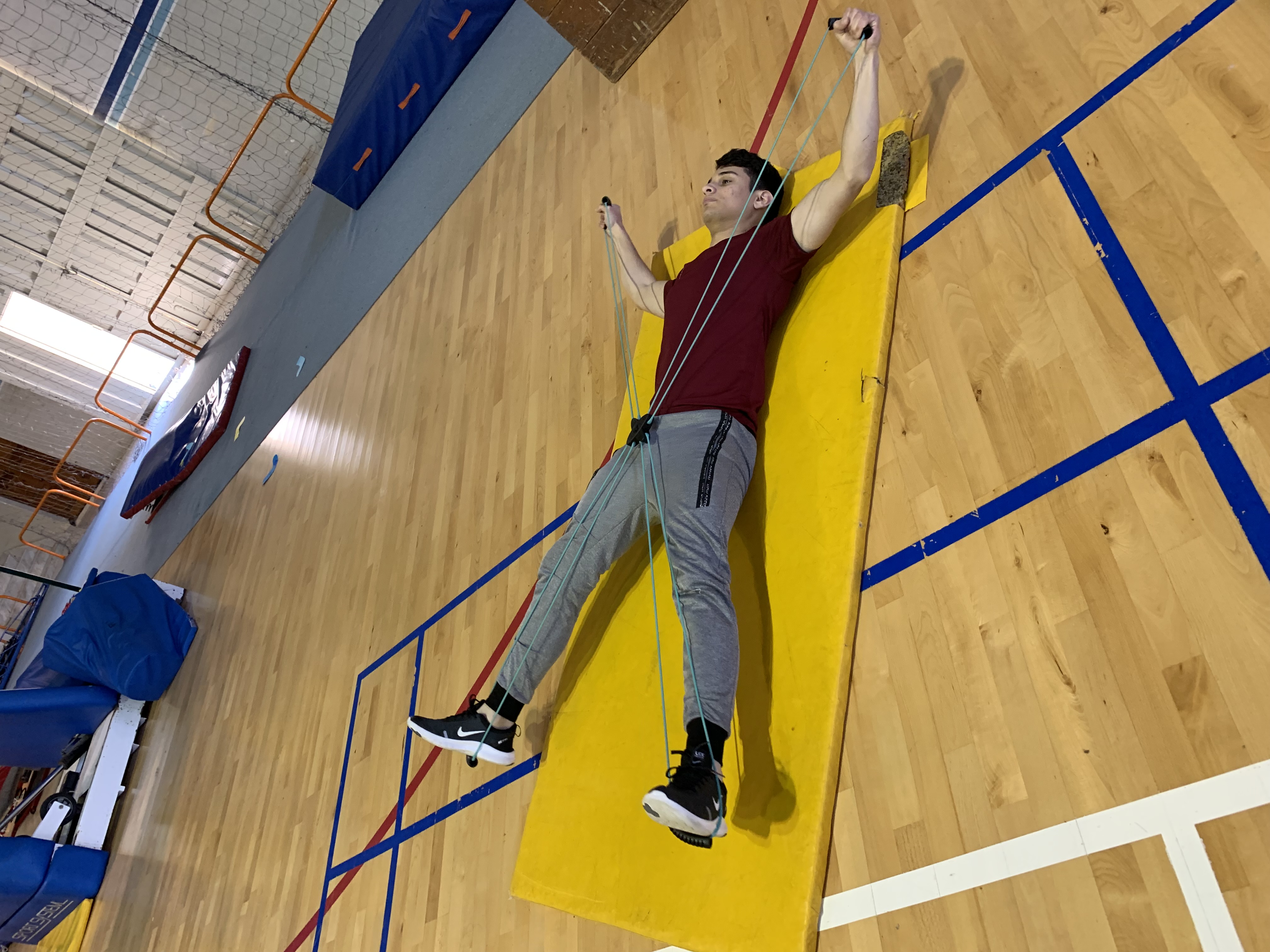 A student doing physical exercises on a mat.