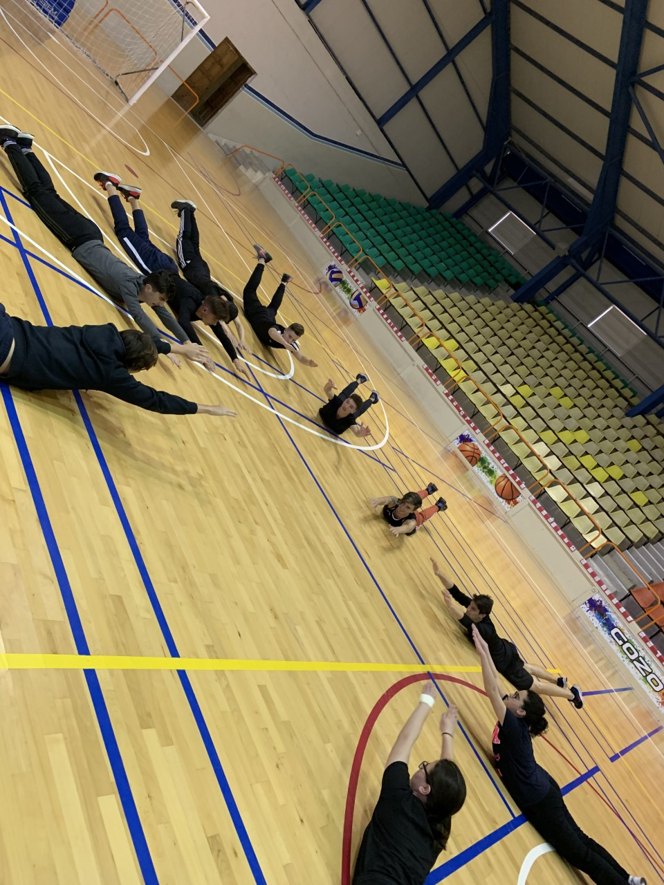 students doing stretching on a gym floor